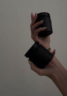 two hands holding black cups in each other's palms, both with their fingers on them