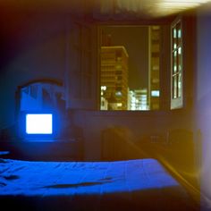 an image of a bedroom setting at night with the tv on and no one in it