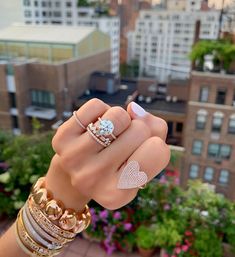 a woman's hand with several rings on top of it and two heart shaped diamonds