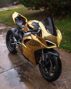 a gold and black motorcycle parked in the rain