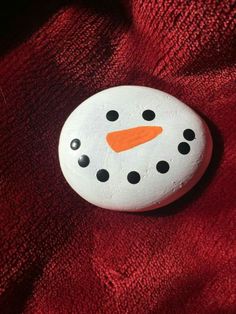 a white button with an orange nose and black dots on it sitting on a red cloth