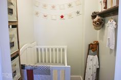 a baby's room with a crib and teddy bear hanging on the wall