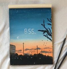 the clock is displayed on top of a painting with two paintbrushes next to it