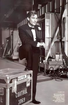 a man in a tuxedo standing next to a suitcase