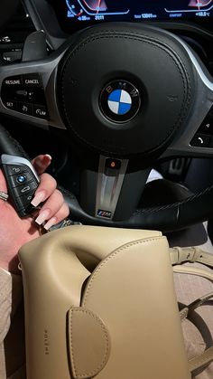 a woman holding a cell phone in her hand while sitting next to a car steering wheel