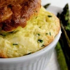 a close up of a bowl of food with asparagus and bread on the side