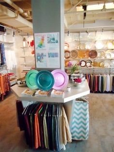 there are many plates on the table in this store that is filled with colorful items