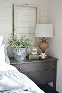 a bedroom with a bed, nightstand and mirror on the side table in front of it