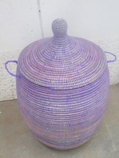 a purple basket sitting on the ground next to a wall