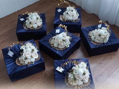 six blue boxes with white flowers in them on the floor next to a wall and window