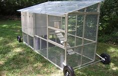 a small chicken coop on wheels in the grass