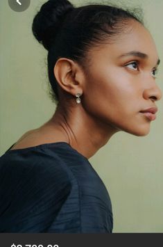 a woman with her head turned to the side, wearing earrings and a black top