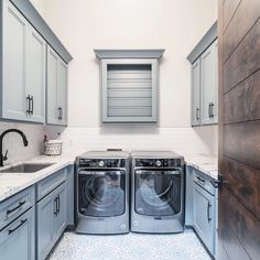 a washer and dryer in a small room with gray cabinets, white counter tops