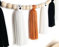 three tassels hanging on a wall with white beads and black ones in the background