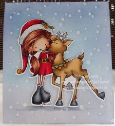 a handmade christmas card with a girl and a deer on the front, wearing a santa's hat