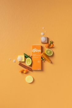 an orange box with some lemons and other items around it on a yellow background