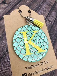 a keychain with the letter k on it and a tassell hanging from it