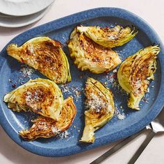 four pieces of artichoke on a blue plate next to silverware and utensils