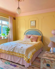 a bed sitting in a bedroom next to a window covered in pink and yellow sheets