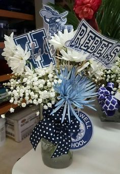 a vase filled with white and blue flowers on top of a table next to a sign