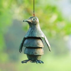 a metal bird feeder hanging from a wire with a green tree in the back ground