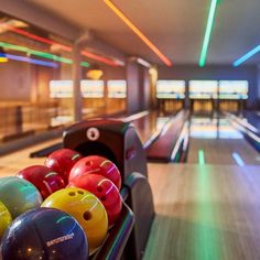 colorful bowling balls in a row at the end of a bowling alley with neon lights