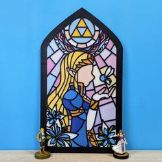 a stained glass window sitting on top of a table next to a figurine