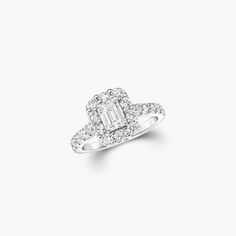 a diamond engagement ring with an emerald center surrounded by round brilliant cut diamonds on a white background