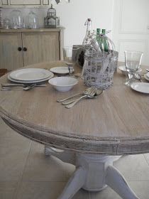 a wooden table with plates, silverware and wine glasses on it in a kitchen