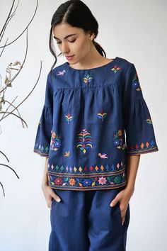 Navy blue top with all over Kutch inspired floral thread work.
Components: 1
Fabric: Cotton linen
Neckline: Wide
Sleeve Length: Three quarters
Color: Blue
Embroidery
Bell sleeves
Closure: Back buttons
Note: Pants worn by the model is not for sale - Aza Fashions Bohemian Embroidered Blue Sets, Bohemian Blue Embroidered Sets, Festive Tops With Geometric Embroidery, Blue Blouse With Geometric Embroidery For Spring, Blue Blouse With Intricate Embroidery For Spring, Spring Blue Blouse With Intricate Embroidery, Blue Folk Top With Geometric Embroidery, Blue Long Sleeve Top With Resham Embroidery, Embroidered Blue Summer Sets