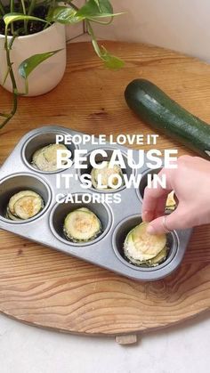 someone placing an egg in a muffin tin with zucchini on the side