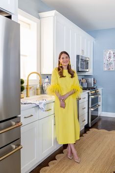 a woman in a yellow dress standing in a kitchen