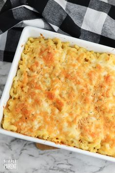 a casserole dish with cheese in it on a marble countertop next to a black and white checkered napkin