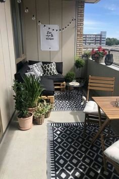 an apartment balcony with black and white rugs, potted plants and wooden furniture