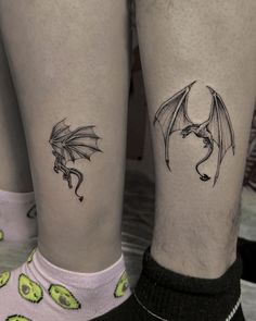 two people with tattoos on their legs, one has a dragon and the other has a skull