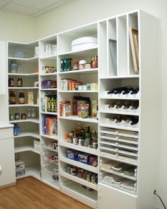 an organized pantry with white shelving and wooden floors