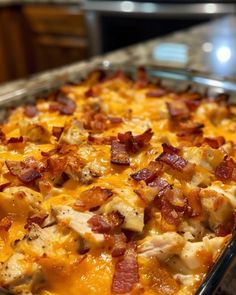 a casserole dish with chicken, bacon and cheese on it sitting on a counter