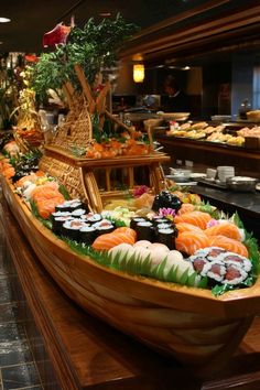 a wooden boat filled with sushi and other food items on top of a counter