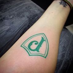 a person with a tattoo on their arm that has the letter c in green ink