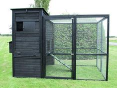 a small black chicken coop in the grass