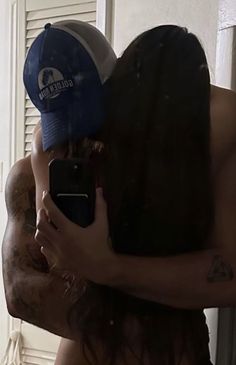 a shirtless man taking a selfie in front of a mirror with his hat on