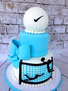 a three tiered cake with a soccer ball on top and blue ribbon around the edges