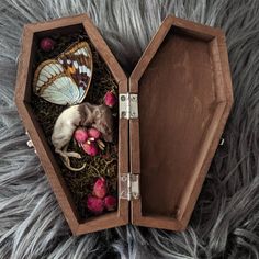 an open wooden box with a mouse and butterflies in it on top of some grass