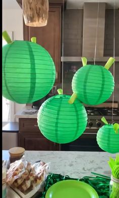 three green paper lanterns hanging from the ceiling above a kitchen counter with plates and cups on it