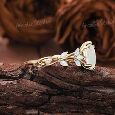 an opalite and diamond ring sitting on top of a piece of drift wood