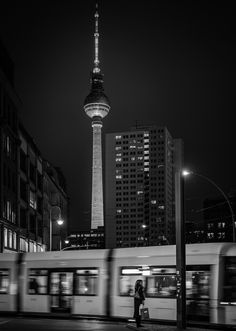 a black and white photo of a train passing by in front of a tall building