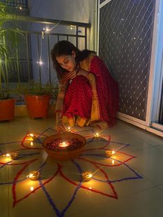 a woman sitting on the floor in front of a potted plant with lit candles