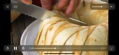 someone is cutting up some food on a plate with a knife and video player in the background