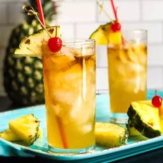 two glasses filled with pineapple punch on a blue tray