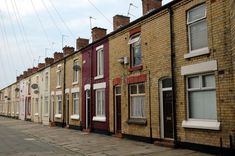 a row of brick houses with windows and shutters on either side of the street